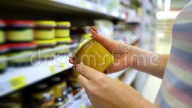 接近白种人的女人手靠近商店货架，在杂货店里选择淡蜂蜜